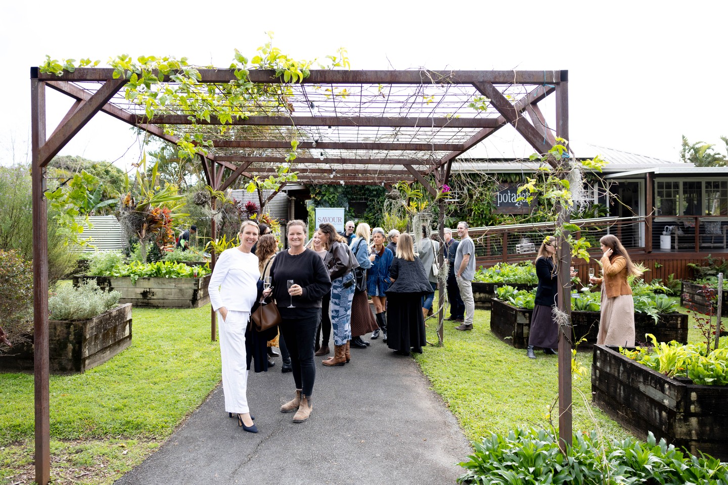 Visitors gathering beneath a vine-covered pergola in Potager’s kitchen garden